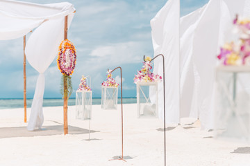 Romantic wedding ceremony on the beach, flowers and candles with white decoration. Honeymoon and wedding beach background concept