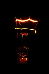 closeup of a lightbulb with a glass filament. extreme macro shot of light bulb filament on black...