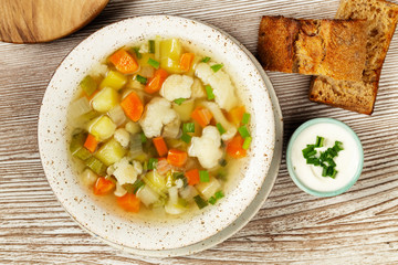 Vegetables soup with cauliflowers, onion, celery, carrots, tomatoes, potatoes, peas, zucchini.	