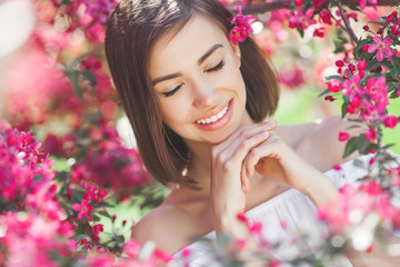Obraz na płótnie Canvas Beauty portrait. Young attractive woman with flowers. Closeup picture of beautiful lady outdoor on spring background. Pink petals.