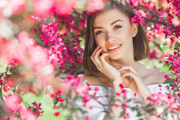 Obraz na płótnie Canvas Beauty portrait. Young attractive woman with flowers. Closeup picture of beautiful lady outdoor on spring background. Pink petals.