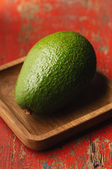 Whole avocado on red background