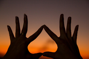 hand sign against sunset
