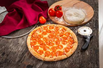 Hot pepperoni pizza ready to eat. Fresh pizza with tomatoes, cheese on old wooden table with...
