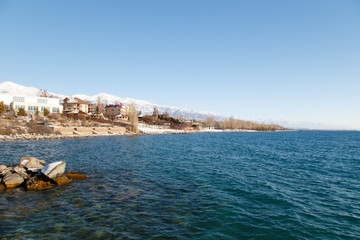 Winter beach. Blue clear sea water. View from the sea to the shore. Kyrgyzstan