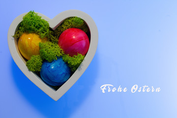 coloured Easter eggs in the wooden heart with real moss and Easter greetings