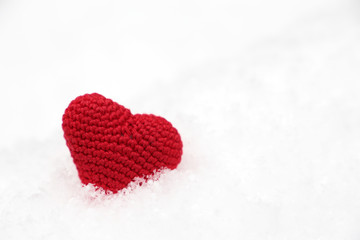 Fototapeta premium Valentine's day, red knitted heart in the snow. Background for romantic event, celebration or winter weather