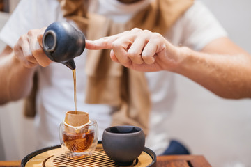 Hands of a man with a teapot during the ceremony of brewing and drinking tea.