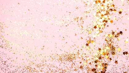 Pink confetti and golden stars and sparkles on pink background. Top view, flat lay. Copyspace for text. Bright and festive holiday background. For Christmas, New year, Mother's day.