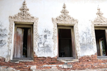 Fototapeta na wymiar Windows of ancient church in Bangkok, base of church is broken and open some red bricks, stucco of Thai pattern around the window, Thailand.