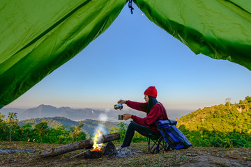 view of tent of woman traveller enjoy hot drink in front of living tent, prepare hot drink in the...