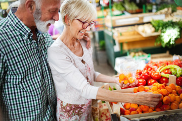 Senior family couple choosing bio food fruit and vegetable on the market during weekly shopping