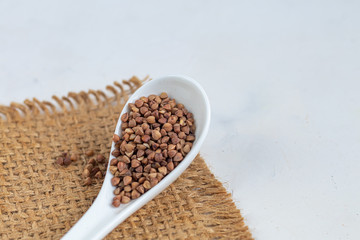 Buckwheat raw, medium rare. Measured for making porridge. On a gray background under concrete.