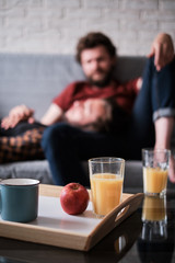 Cups and glasses stand on the table with a gay couple on the background.