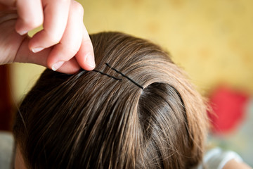 Fototapeta premium Girl pins her hair with a metal barrette