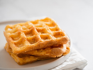 Perfect savory keto waffles. Two ingredients chaffles on plate over white marble background. Eggs and parmesan cheese low carb waffles.