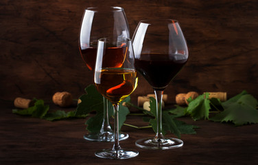 Wine set. Red, white and rose wine in assortment in wineglasses. Wine tasting, vintage wooden background, selective focus, copy space