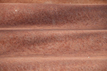 Red brown zinc rust on wave shape zinc plate background.