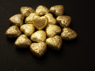 Golden glitter covered hearts design on dark background. Saint Valentine theme.
