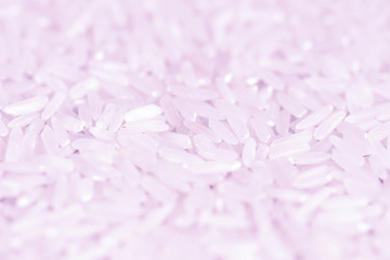 White rice grains scattered on a wooden surface close up. Food background pink color toned