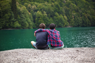 Fototapeta na wymiar Young stylish couple of travelers looks at a mountain lake. Travel and active life concept.