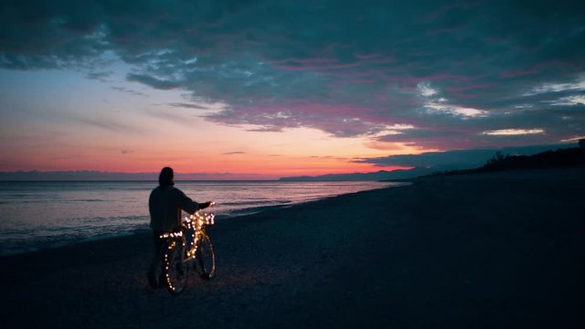 San Valentino, la festa degli innamorati. Ragazza da sola in bici la notte vicino al mare