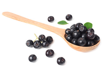 Chokeberry in wooden spoon isolated on white background. Black aronia