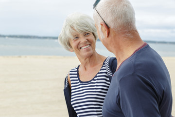 senior couple sitting on beach together