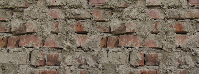 Old brick wall texture. Close-up. Sloppy brickwork. Detail. Red stone grunge background. Uneven masonry. Abstract distressed brown background.