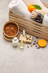Coffee and tangerine spa concept. Towels, oil, scrub, soap, lotion. Natural ingredient, wooden box. Stone concrete background