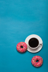 A cup of americano with two pink donuts on a blue background