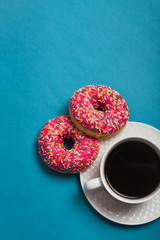 A cup of americano with two pink donuts on a blue background
