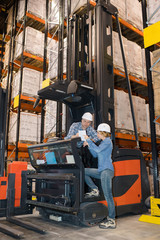 woman using tablet next to man on forklift