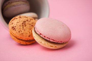 Closeup of french macarons and cup of coffee on pink background