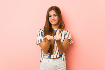 Young slim woman holding something with palms, offering to camera.