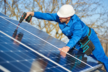 Man worker in blue suit and protective helmet installing solar photovoltaic panel system using...