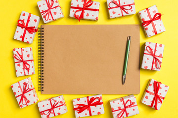 Top view of notebook surrounded with gift boxes on colorful background. Valentine's Day concept