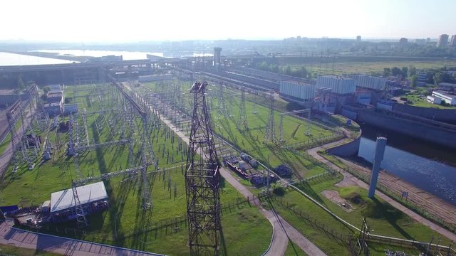 High voltage electric power tower, electric substation, hydroelectric power station, power distribution. Aerial quadrocopter orbit circle fly. Cars and trucks traffic, early morning spring summer sun.