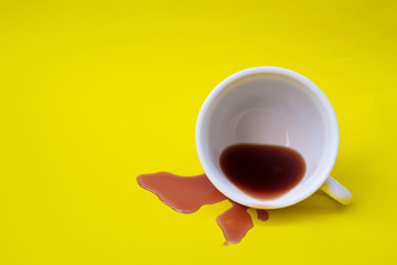 Coffee spilled from the cup onto a yellow background