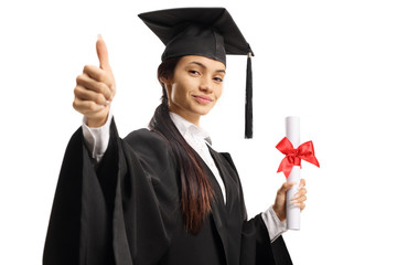 Female student in a graduation gown holding a diploma and showing thumbs up