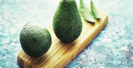 Avocado cooking recipes. Ripe green avocado on a wooden cutting board for serving.