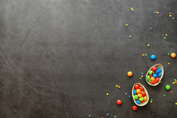 Easter background on black stone. Multicolored eggs and sweets.