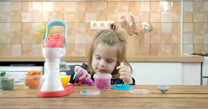 Little baby girl playing with colorful dough 