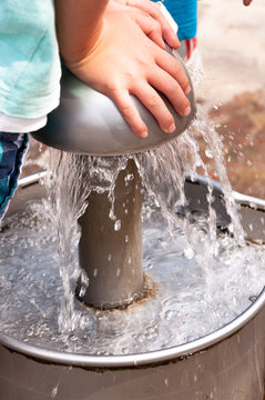 Am Wasserspielplatz, Kind dr&uuml;ckt nach unten und Wasser beginnt zu flie&szlig;en