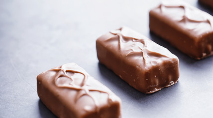 Chocolate bars on a black background in backlight. Chocolate with filling. Sweet sweets for snack and tea.