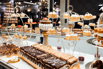Delicious wedding reception candy bar dessert table full with cakes and sweets. Luxury life. Bithday cakes and accesories. Party and celebration. Colorful cakes. Dessert table for a party. 