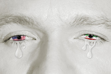 Crying eyes with the American flag and Iranian flag in irises on black and white face. Concept of sorrow for world conflict and war, patriotic metaphor.