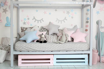 Interior of a children room with a wooden bed in shape of house. Home decor. A cozy Scandinavian style children bedroom with crafts,toys and cute pillows. Bedding and textiles for children nursery. 