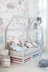 Interior of children room with toys. Scandinavian design of a children's room with a wooden bed in the shape of house, designer furniture, soft toys and pillows. Home decor. Kindergarten. playroom
