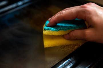 Woman cleaning dirty and greasy oven with stove in kitchen.